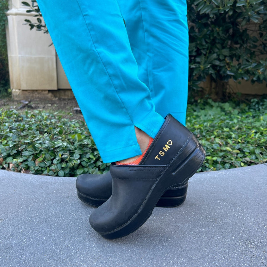 A nurse wearing black personalized clogs.