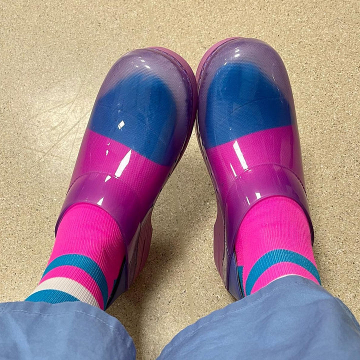 User generated content of healthcare professional showing off their purple translucent clogs with bright purple socks.