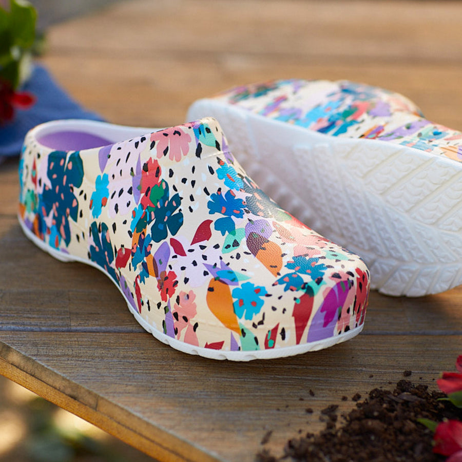Primary lifestyle image of Kane Flower Party Mules on wooden tabletop outdoors